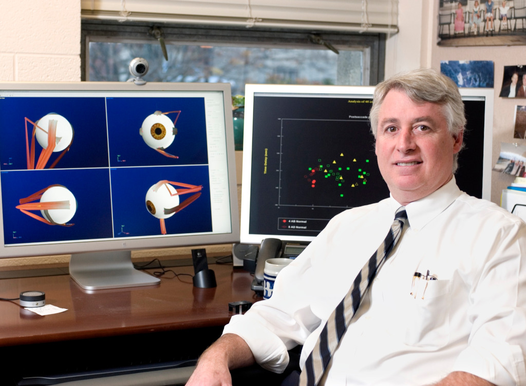 dr. john enderle sitting in front of two computers