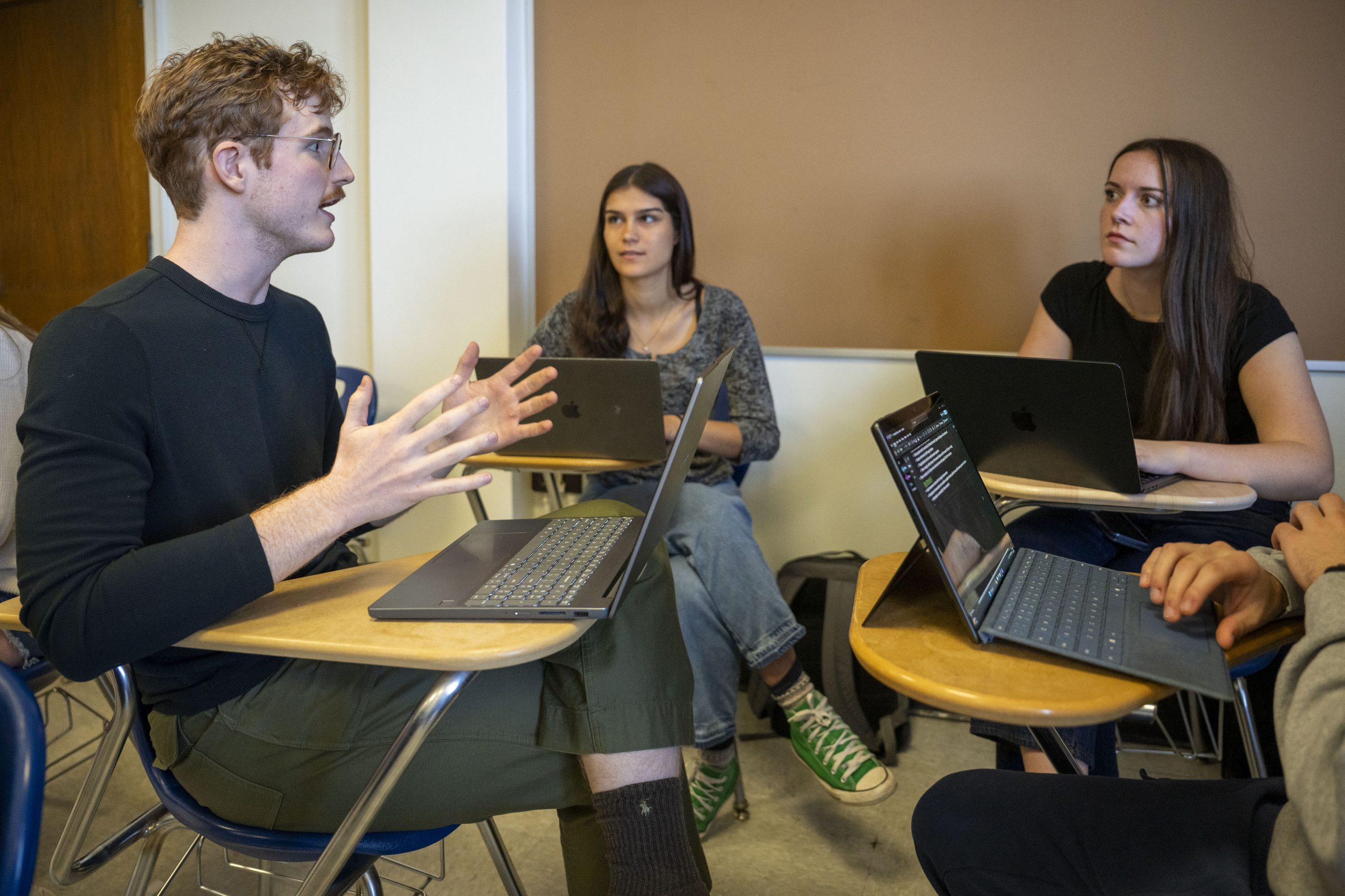 four students in class sitting down discussing a topic